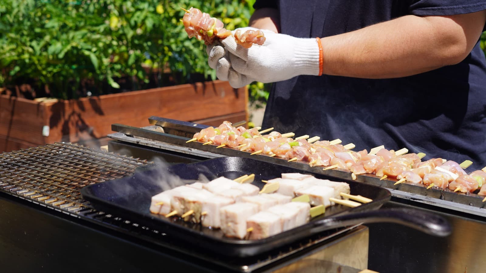 Chef placing chicken skewers on the grill, hands in cotton gloves