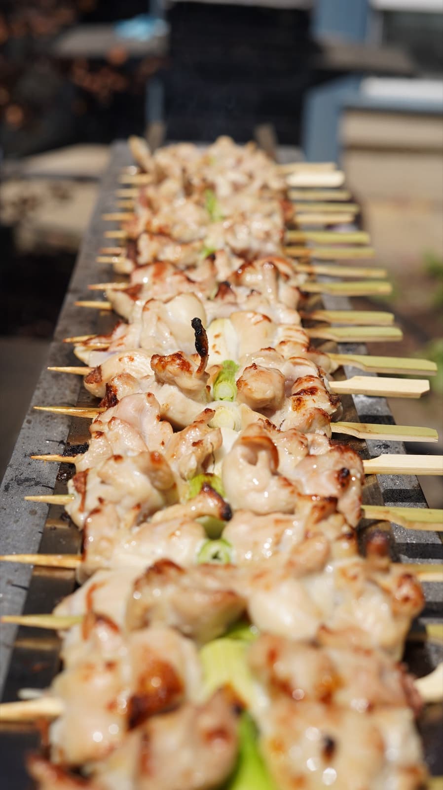 Rows of chicken skewers grilling over binchotan