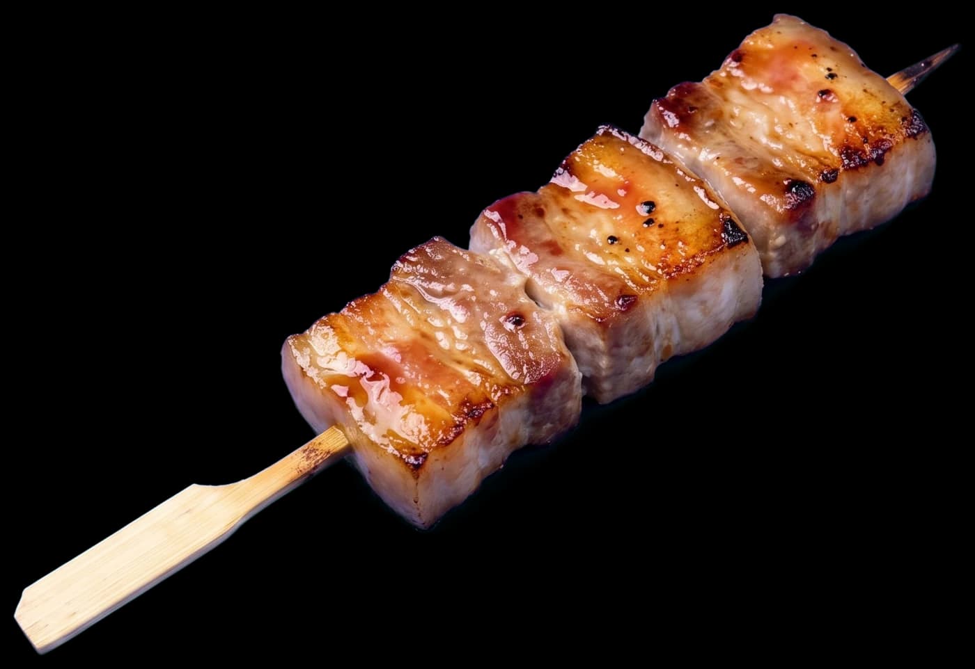 A butabara skewer: thick pieces of pork belly seared golden and brushed with umeboshi miso glaze