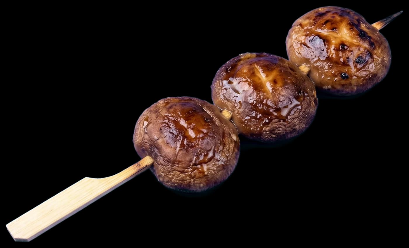 A shiitake skewer: three whole caps grilled glossy brown with soy butter