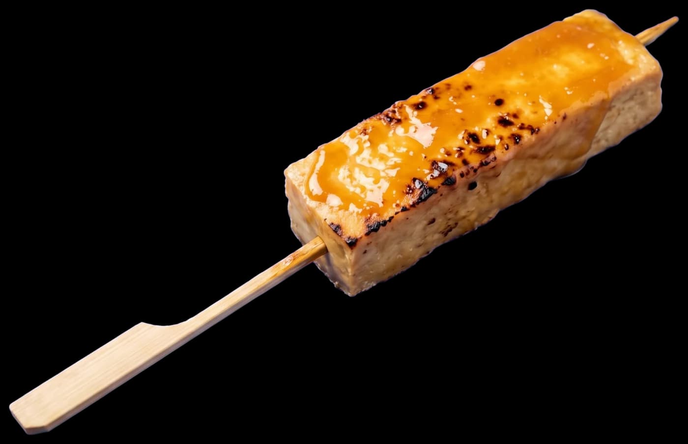 A piece of grilled tofu on a skewer, brushed with a glossy miso glaze